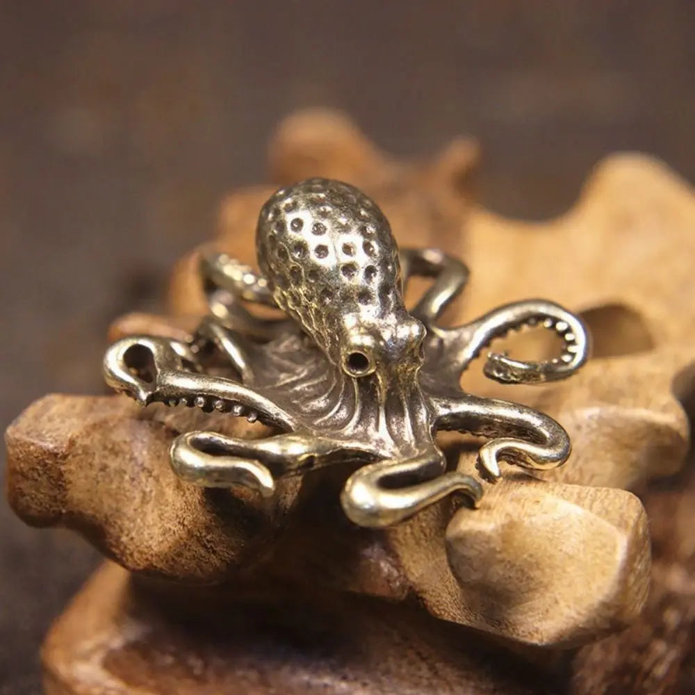 Antique brass octopus desk ornament resting on a wooden surface.