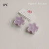 One piece of a handmade soy wax flower tea light candle in light purple color packaged with a label