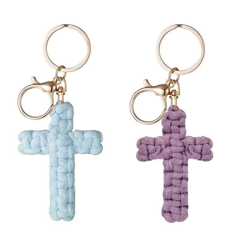 A pair of bohemian woven cross keychains, one light blue and one purple, with gold-toned rings.
