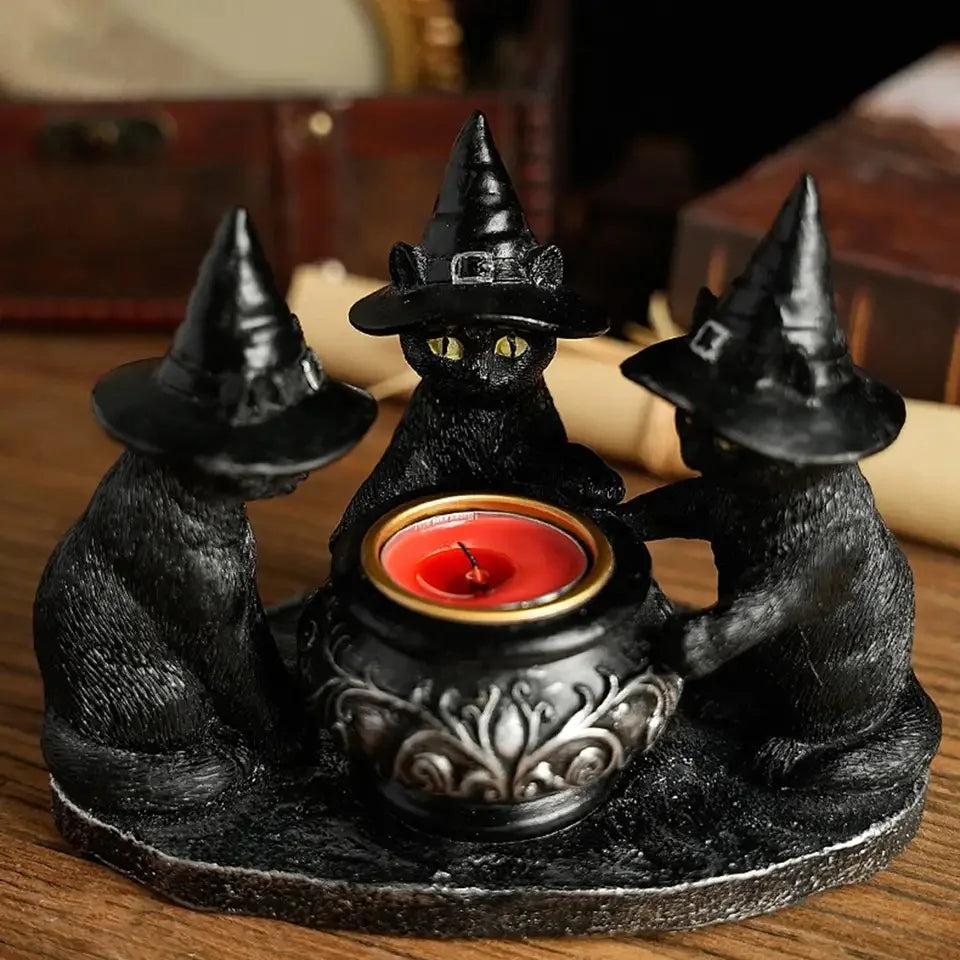 A black figurine of a cat wearing a witch hat sitting on a candle holder.