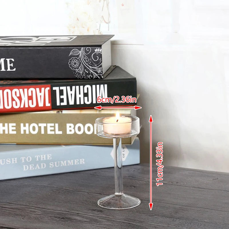 Elegant tall glass candle holder with a white candle placed in front of stacked books.
