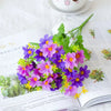 A bouquet of purple and pink artificial daisy flowers with green foliage displayed on a white page.