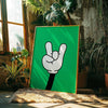 Arte en lienzo verde brillante con un signo de mano blanco contra un ambiente rústico interior con plantas.