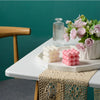 A set of two white and pink cube soy wax candles displayed on a white platter with pink roses.