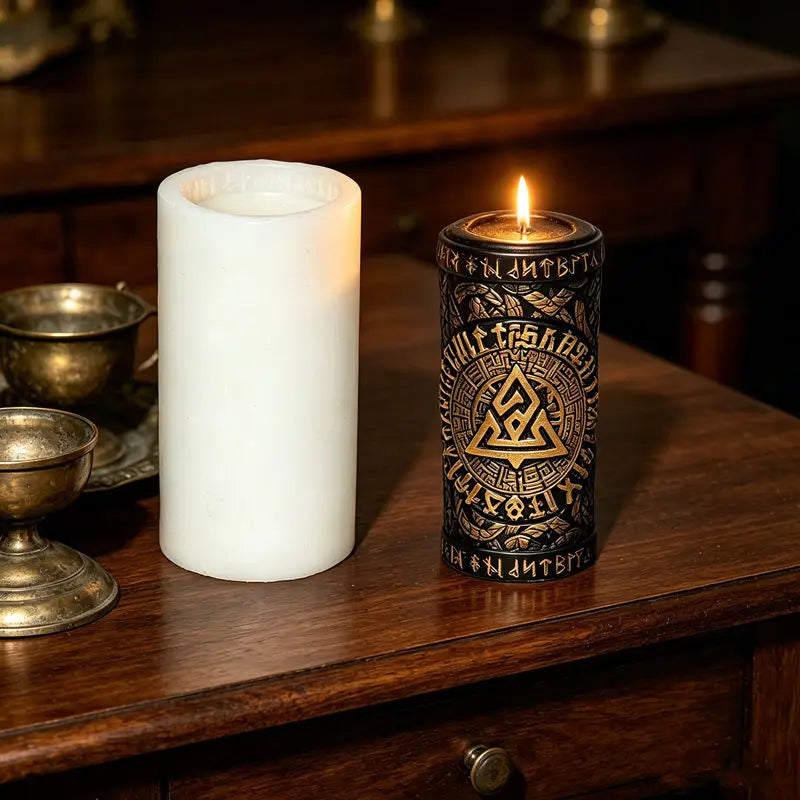 A white pillar candle and a dark metal tin candle with a flame are displayed on a wooden surface.