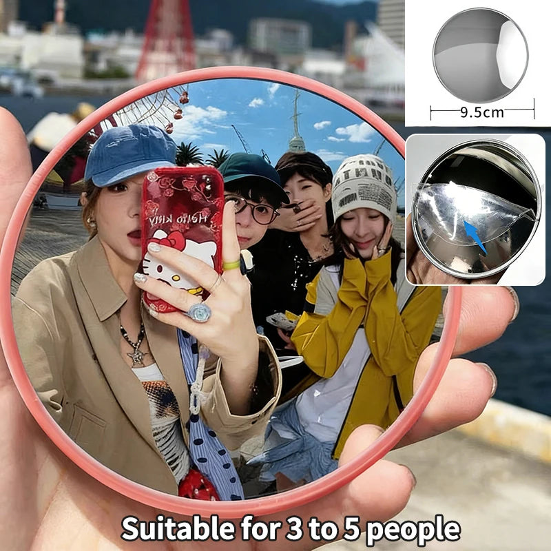 A round convex mirror is held by a person, showing a group of people in the background.