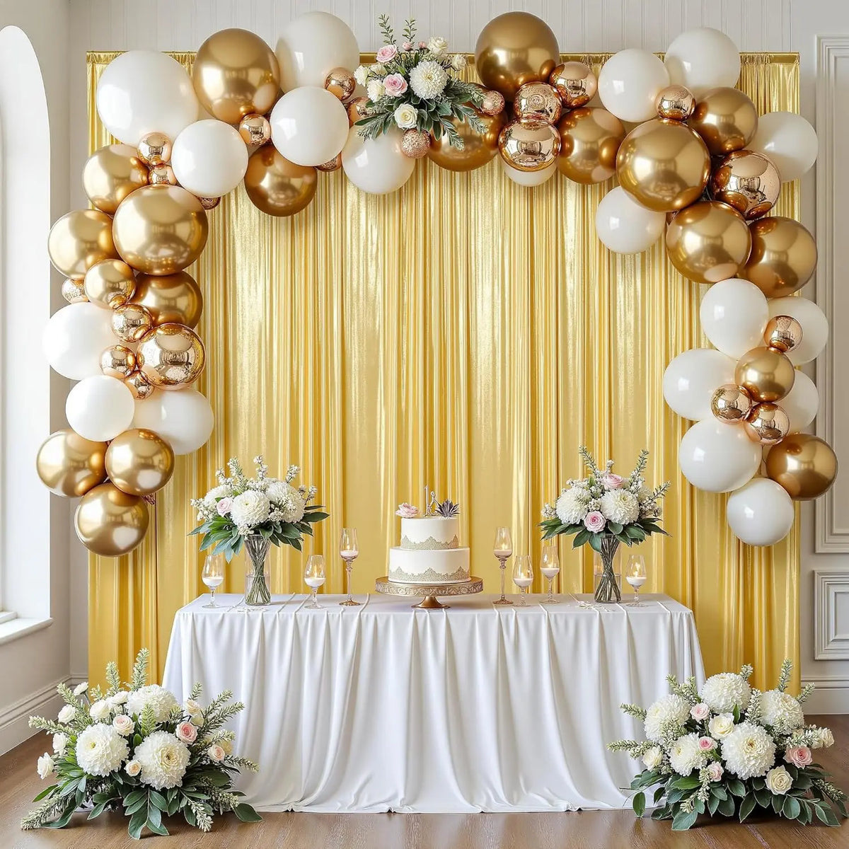 A golden sequin backdrop curtain decorated with white and gold balloons and floral arrangements for an event.