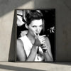 Black and white portrait of a woman with her hair styled up, holding a cigarette, against a dark background.