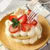 A close-up shot of a strawberry and cream dessert served on a plate with a fork.