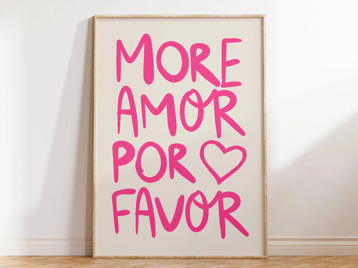 A framed canvas print featuring the pink text MORE AMOR POR FAVOR on a light background.