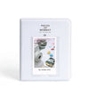 A white sleeve holding a piece of paper with the text Pieces of Moment and an inset photo for Instax mini cameras.