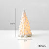 A white ceramic glow-in-the-dark mini Christmas tree decor shaped like a conical pine tree.
