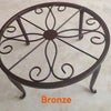 A decorative bronze metal plant stand with a circular saucer design.