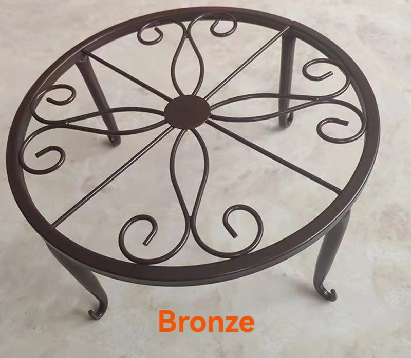 A decorative bronze metal plant stand with a circular saucer design.