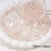 A small glass measuring cup filled with round, translucent pink spacer beads on a white dish.