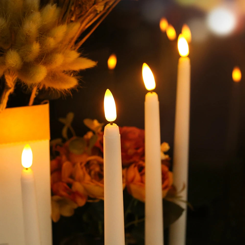 A close-up of several lit white taper candles in a dark setting with blurred orange flowers and soft bokeh lights.
