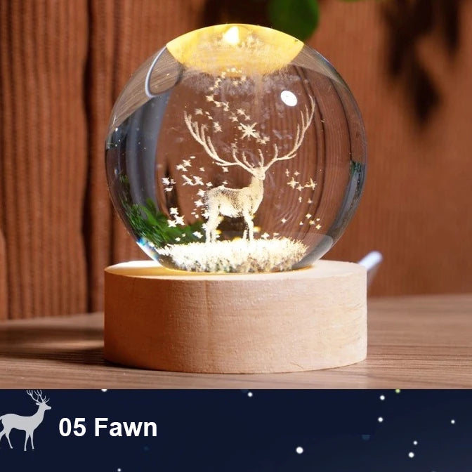A glass crystal ball night light featuring a deer silhouette and stars, resting on a wooden base.