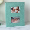 A teal linen-covered photo album with two square pockets displaying photos of a couple.