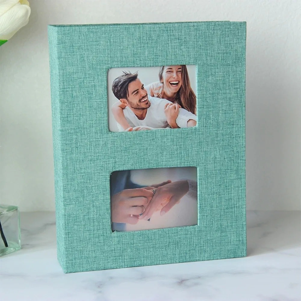 A teal linen-covered photo album with two square pockets displaying photos of a couple.