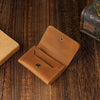 A brown vintage leather card holder and cable organizer resting on a dark wooden surface.