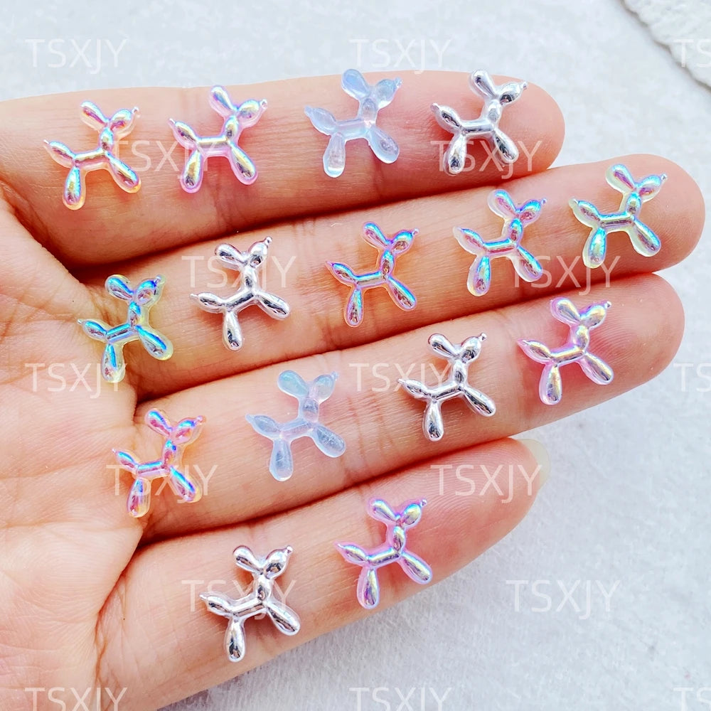A hand displays various clear and iridescent balloon puppy nail art charms on the fingernails.