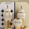 A set of golden and white striped ceramic art vases displayed on a light surface.