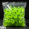 A clear plastic bag filled with numerous bright lime green glow-in-the-dark resin charms shaped like aliens and ducks.