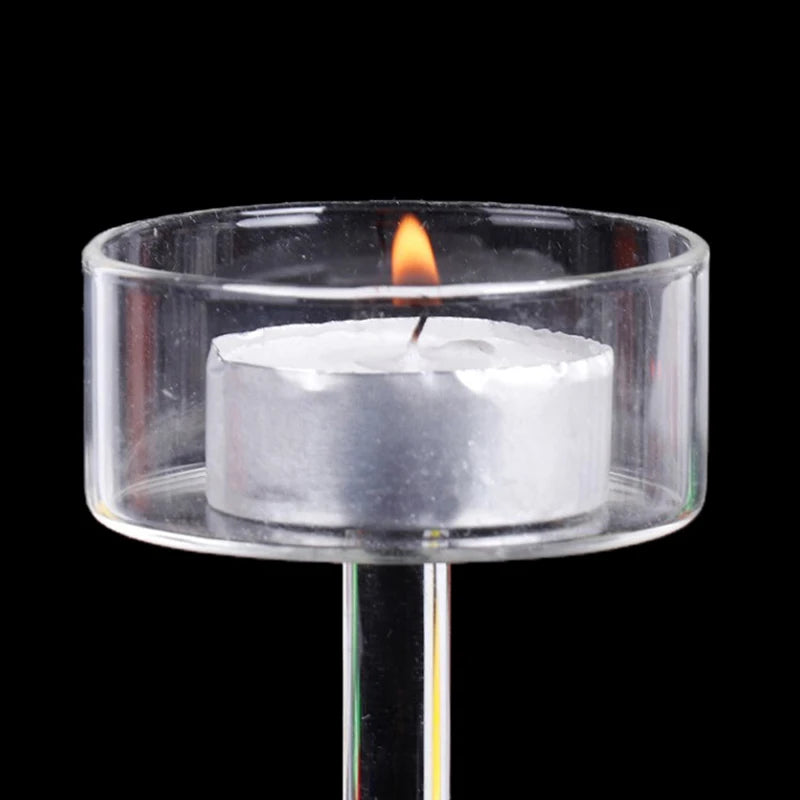 Elegant tall glass candle holder with a lit white candle on a clear glass base.