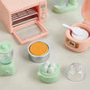 A pink kitchen appliance dollhouse set featuring a food processor, a grinder, and various accessories like eggs and spices.