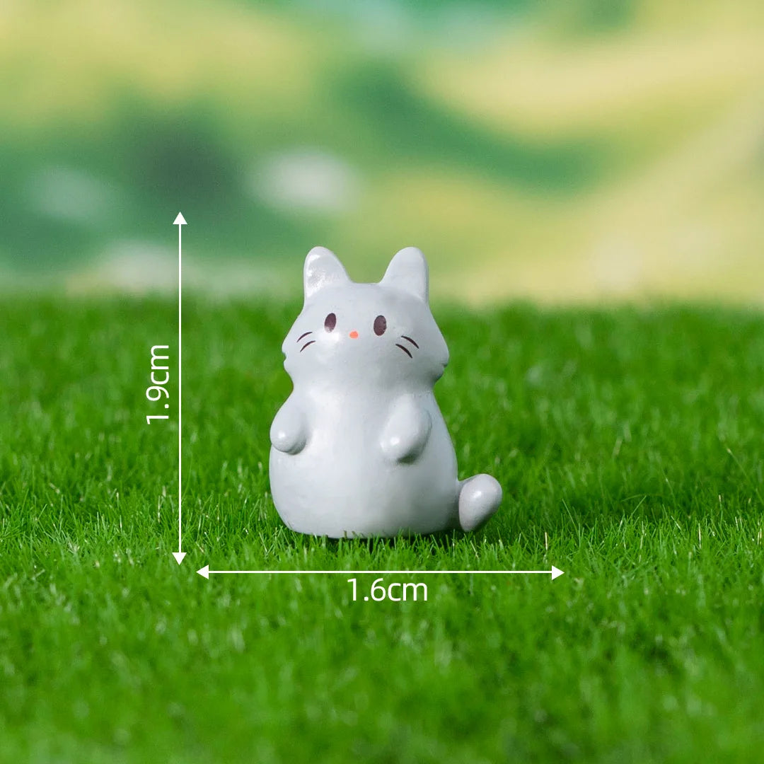A small white cat figurine sitting on green grass with dimension markings.