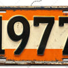 Señal de pared de aluminio vintage con el año 1977 en números negros sobre fondo naranja.