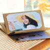 A photo album with a gold frame displaying a portrait of a smiling young girl wearing a yellow hat.