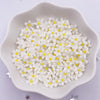 A white dish filled with small white and yellow resin flower gems for crafts