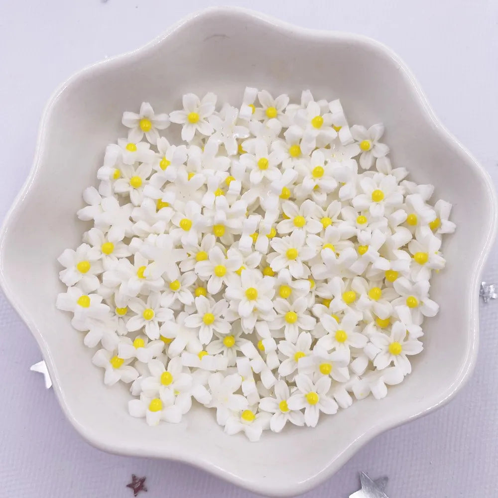 A white dish filled with small white and yellow resin flower gems for crafts