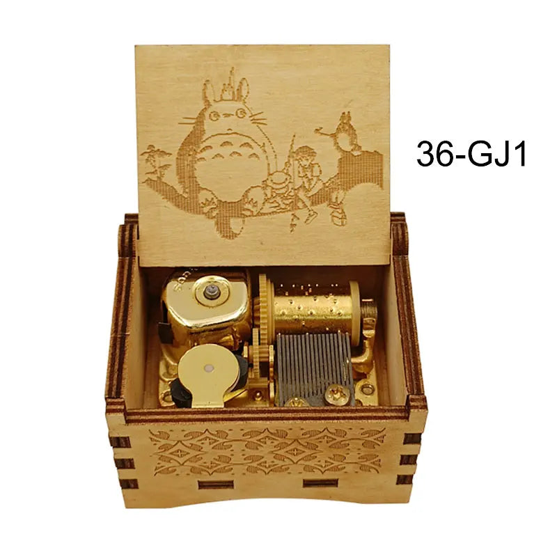 A wooden box containing a brass music box with a decorative lid featuring anime characters.