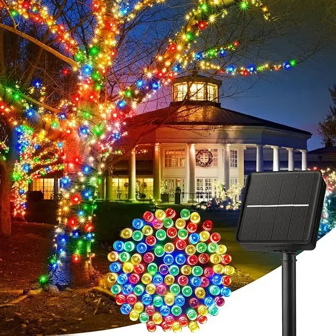 Solar-powered LED string lights illuminating a tree and a building at night