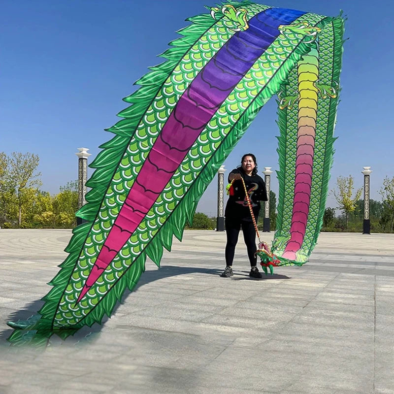 Una mujer realizando una danza de dragón con un gran accesorio de tela verde y morada colorido al aire libre.