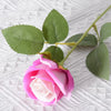 A pink and white artificial rose with green leaves on a stem, suitable for wedding or home decor.