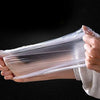 Hands holding a clear plastic wrap containing disposable elastic bowl covers for food.