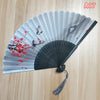 A light blue and black folding hand fan decorated with red blossoms and branches.