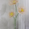 A large artificial silk poppy flower with pale peach petals is displayed on a green stand against a white background.