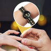 A hand holds a silver ring and a close-up inset shows an adjustable black watch or bracelet with numbers.