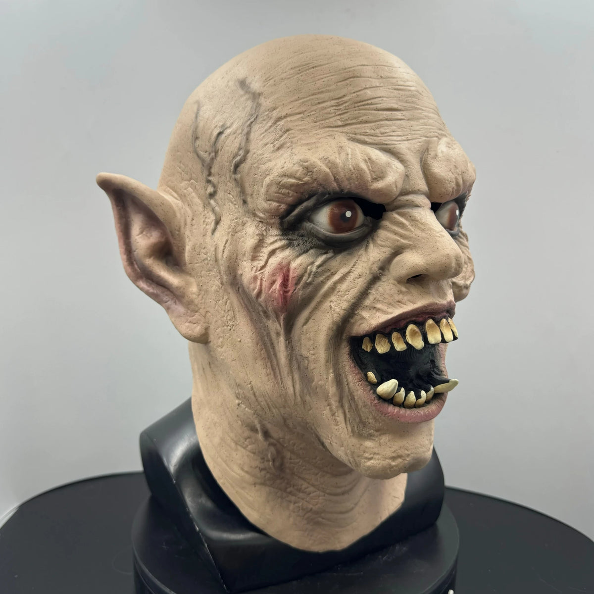 A realistic demon latex mask featuring wrinkled skin, sharp teeth, and an elf-like facial structure.