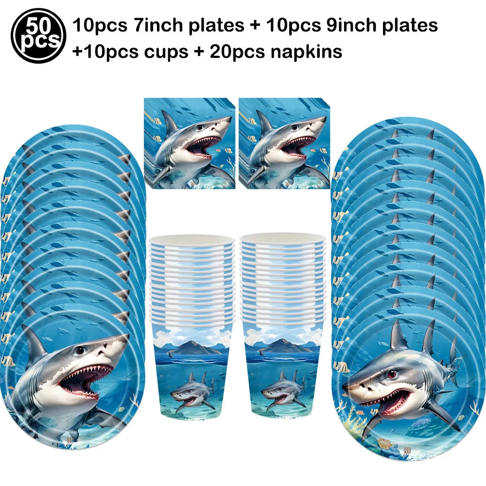 Set of blue shark foil balloons and various plates cups and napkins for an ocean-themed party decoration
