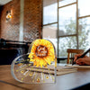 A heart-shaped sunflower plaque with Bible verses engraved on it rests on a wooden table.