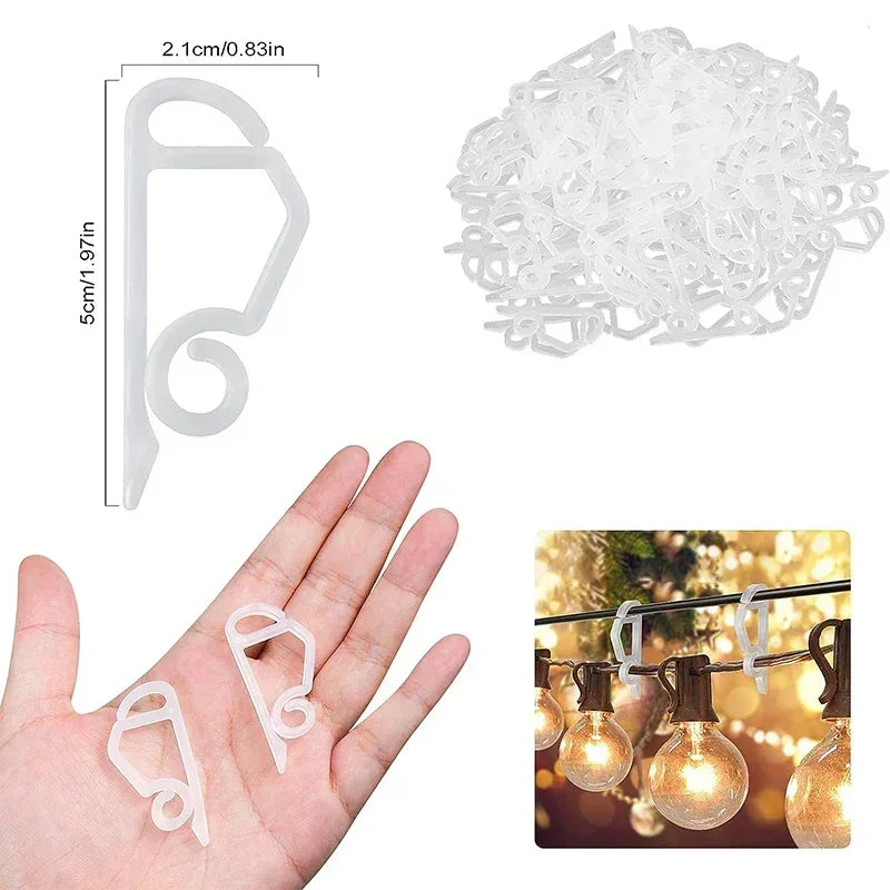 A hand holds small white wire clips used for hanging outdoor string lights.