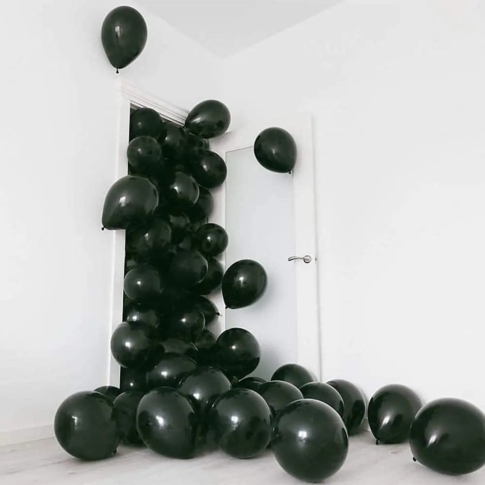 A cluster of black latex balloons is displayed against a white wall.