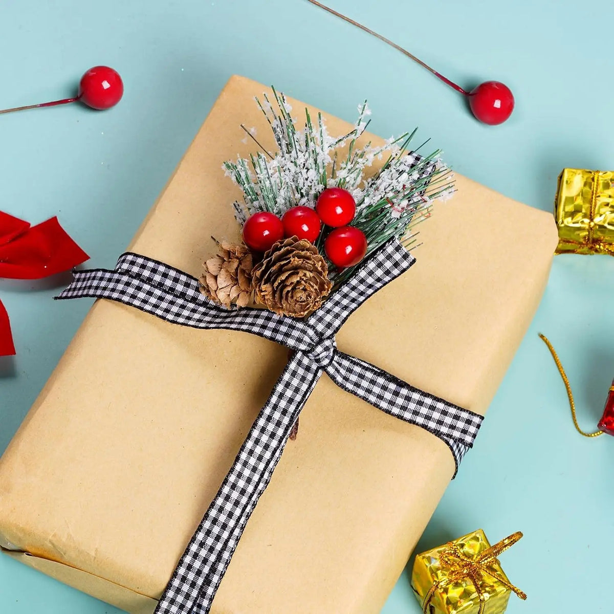 Un regalo envuelto en papel kraft atado con una cinta a cuadros blanco y negro, decorado con bayas y pino artificial