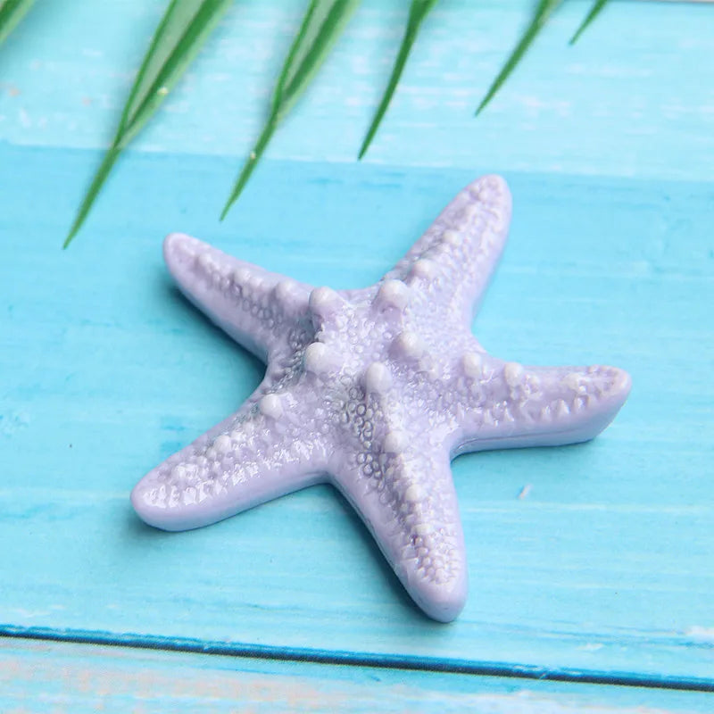 A purple starfish ocean animal cake topper set featuring a starfish shape on a light blue wooden background.