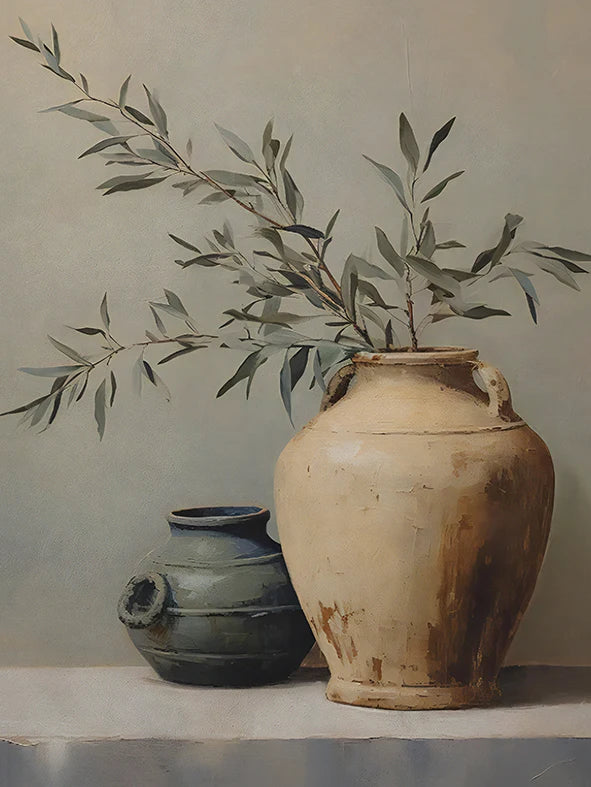 A ceramic vase holds a branch of olive leaves against a light gray background.